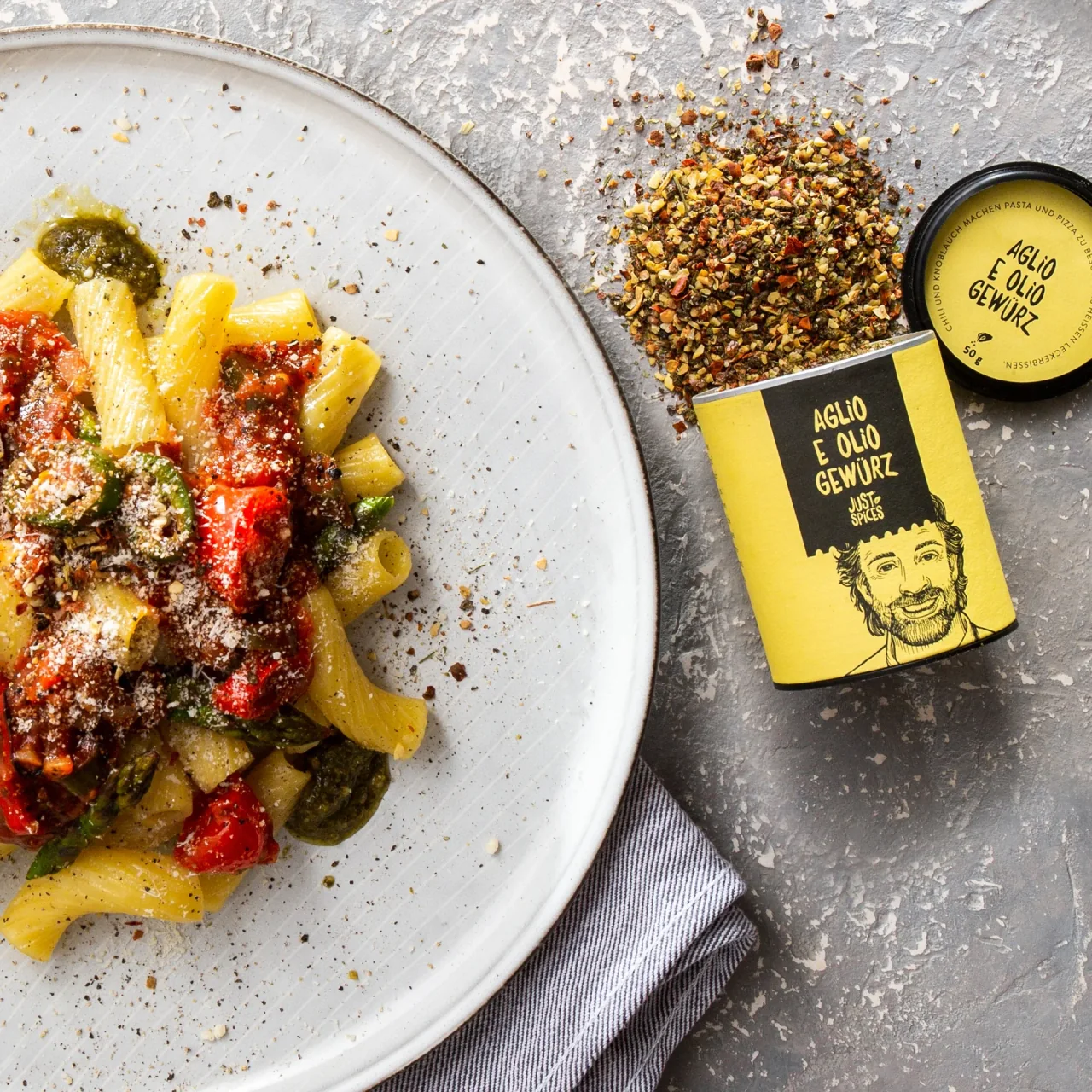 Close-up of pasta beside an open Just Spices jar and scattered seasoning